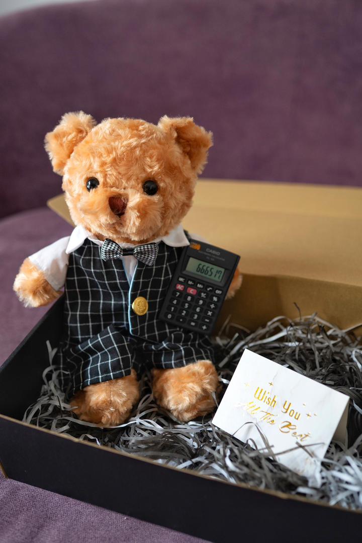 Accountant Bear — A charming handcrafted teddy bear in a sharp plaid suit, bow tie, and carrying a Casio calculator. Personalised with a name — the most unique gift for an accountant or finance graduate.